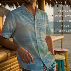 May include: A short-sleeved button-down shirt with a blue and green watercolor design. The shirt is worn by a person leaning on a bamboo bar. The text on the image reads "Instant Product Previews - Just Add Your Design."