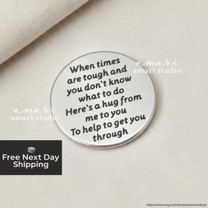 May include: A circular silver keepsake with engraved text. The text reads: "When times are tough and you don't know what to do. Here's a hug from me to you to help to get you through."