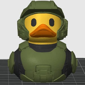 Puede incluir: Un pato de goma amarillo con un casco y una armadura militares verdes. El pato tiene un pico de color naranja brillante y ojos negros. El casco y la armadura están detallados con varios paneles y formas. El diseño es una versión lúdica del tema militar.