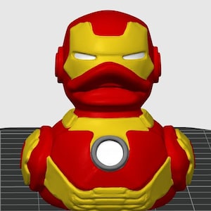 Puede incluir: Un patito de goma rojo y amarillo con el estilo de Iron Man. El pato tiene una cabeza y un cuerpo rojos con detalles amarillos, incluyendo el casco y el pecho. El pecho presenta un elemento circular gris.