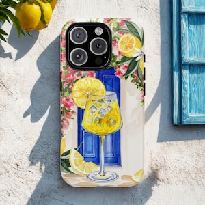 Può includere: Custodia per telefono con un'illustrazione ad acquerello di un cocktail al limone con cubetti di ghiaccio, una fetta di limone e una porta blu. La custodia è decorata con limoni e fiori rosa, creando un'atmosfera estiva.