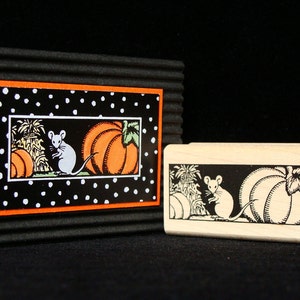 May include: A Halloween-themed rubber stamp and a framed print. The stamp and print feature a black and white illustration of a mouse, pumpkins, and corn stalks. The print has a black background with white polka dots and an orange border.