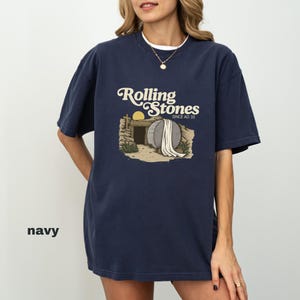 May include: Navy blue t-shirt with a graphic of a tomb and the text "Rolling Stones Since AD 33" in a vintage style. The shirt has a crew neck and short sleeves.