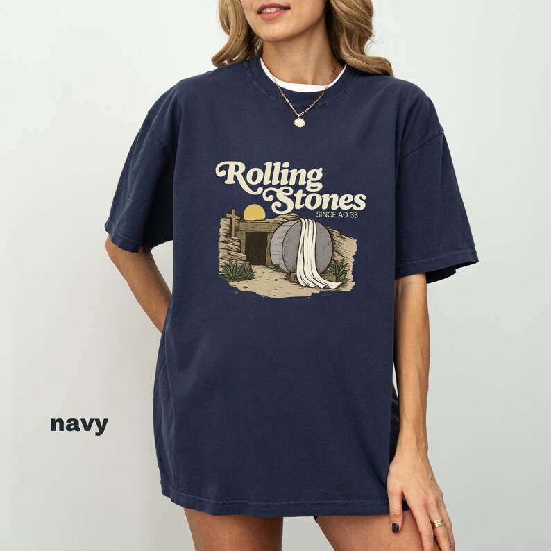 May include: Navy blue t-shirt with a graphic of a tomb and the text "Rolling Stones Since AD 33" in a vintage style. The shirt has a crew neck and short sleeves.