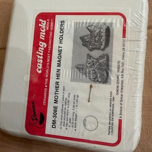 May include: A white plastic casting mold package for ceramic hen magnet holders. The package features a red and white label with product information, including dimensions and weight. The mold produces one piece of each style.