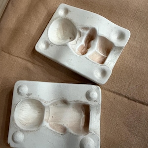 May include: A white ceramic mug with a black handle and the text "But First, Coffee" in a bold, black font. The mug is set against a blurred background, highlighting its clean design.