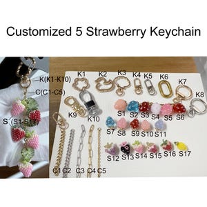 Pu&ograve; includere: Una collezione di portachiavi a forma di fragola personalizzati. I portachiavi presentano vari design, tra cui fragole di perline rosa, rosse e bianche, insieme a diversi stili di catene e chiusure. Il testo "Customized 5 Strawberry Keychain" &egrave; in alto.
