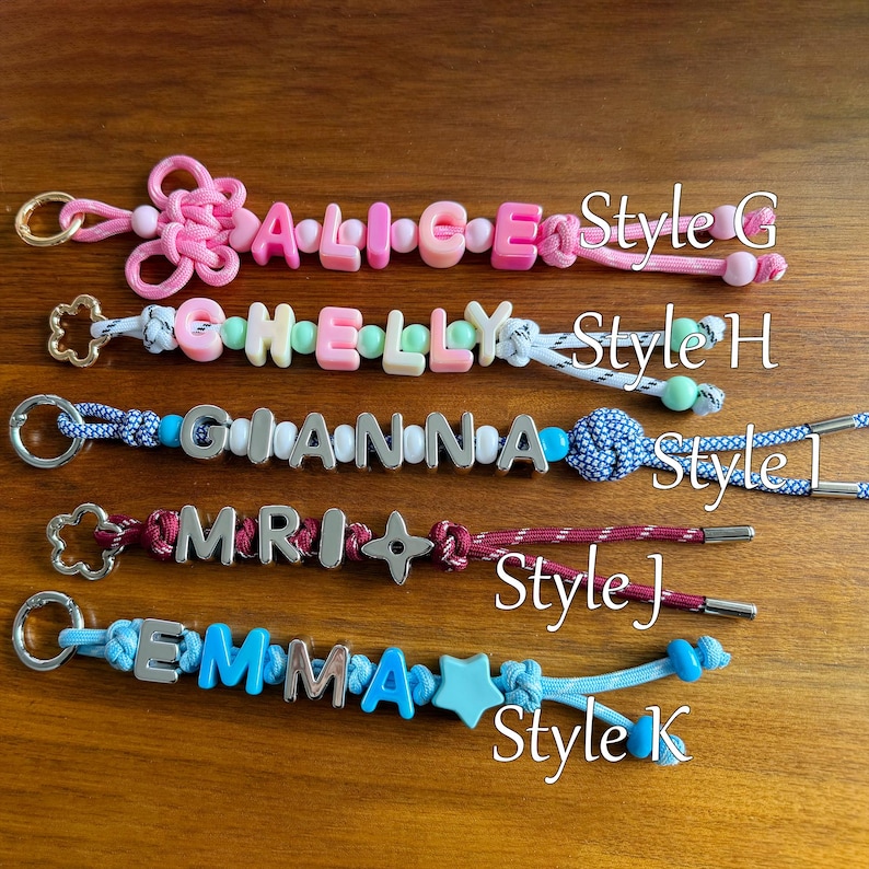 May include: Five personalised keychains with metal rings. Style G features pink cord and beads spelling ALICE. Style H has white cord and pastel beads spelling CHELLY. Style I uses blue patterned cord and silver letters spelling GIANNA. Style J has maroon cord and silver letters spelling MRI. Style K features light blue cord and blue letters spelling EMMA.