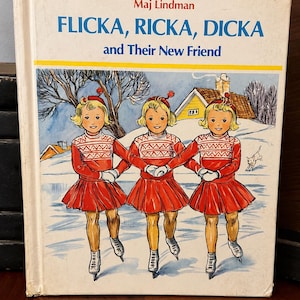 May include: A vintage book titled "Flicka, Ricka, Dicka and Their New Friend" by Maj Lindman. The cover shows three girls in red skating outfits, ice skating on a snowy surface, with a winter scene background.