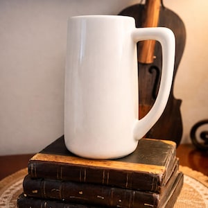May include: A set of three ceramic mugs with a speckled, matte finish. Each mug features a different color: light blue, cream, and gray. The mugs have a simple, modern design and a comfortable handle.