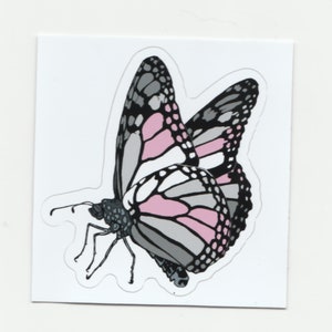 Könnte beinhalten: Ein Aufkleber mit einem Schmetterling mit rosa, weißen und grauen Flügeln. Der Schmetterling ist im Flug und hat seine Flügel ausgebreitet.