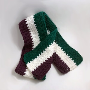 May include: A crocheted scarf with stripes of burgundy, white and forest green.