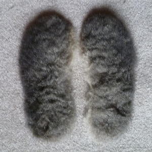 Puede incluir: Dos pompones de piel gris y esponjosa, cada uno de unos 10 cm de diámetro, se muestran sobre un fondo blanco.