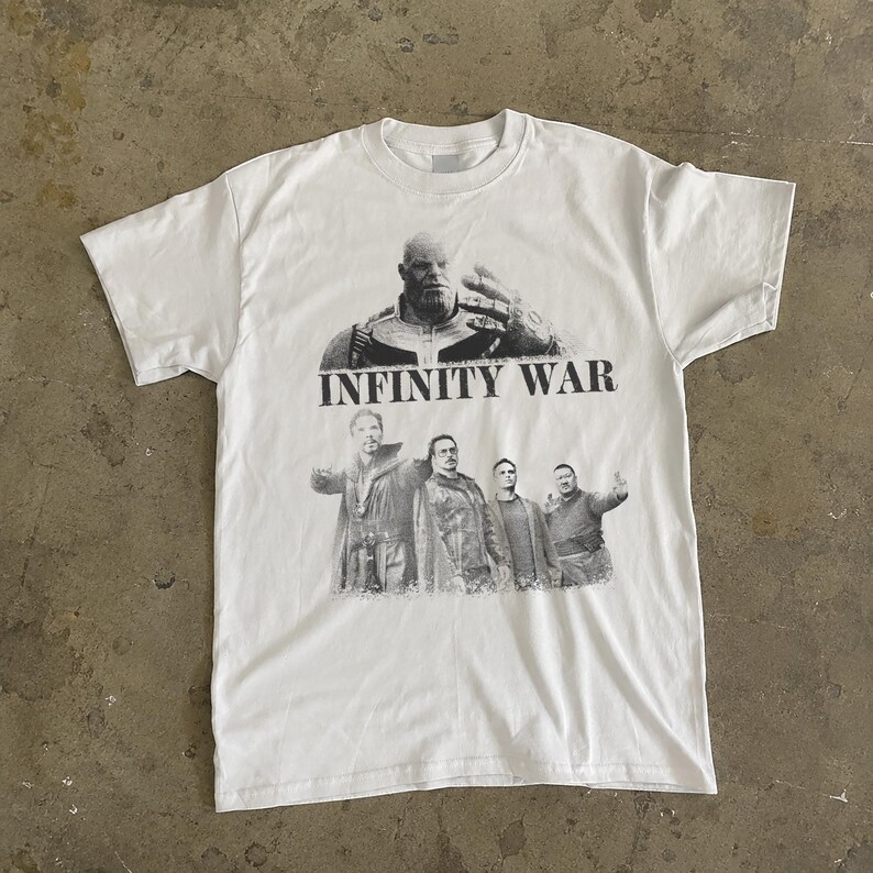 K&ouml;nnte beinhalten: Wei&szlig;es T-Shirt mit einer Schwarz-Wei&szlig;-Grafik von Thanos und anderen Charakteren aus dem Film "Infinity War". Der Text "INFINITY WAR" ist &uuml;ber den Charakteren aufgedruckt. Das Shirt hat einen Rundhalsausschnitt und kurze &Auml;rmel.