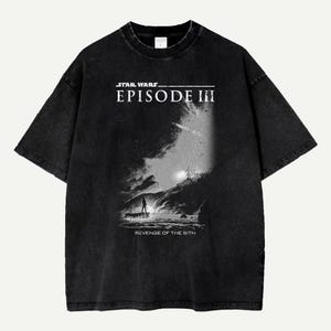 May include: Black t-shirt with a graphic from Star Wars: Episode III - Revenge of the Sith. The design is in monochrome, showing a dramatic scene with figures on a rocky landscape. The shirt has a vintage, washed appearance.