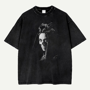 Pode incluir: T-shirt preto com estampa em tons de cinza de uma caveira com adorno floral. A camiseta tem uma aparência vintage e uma gola redonda clássica.