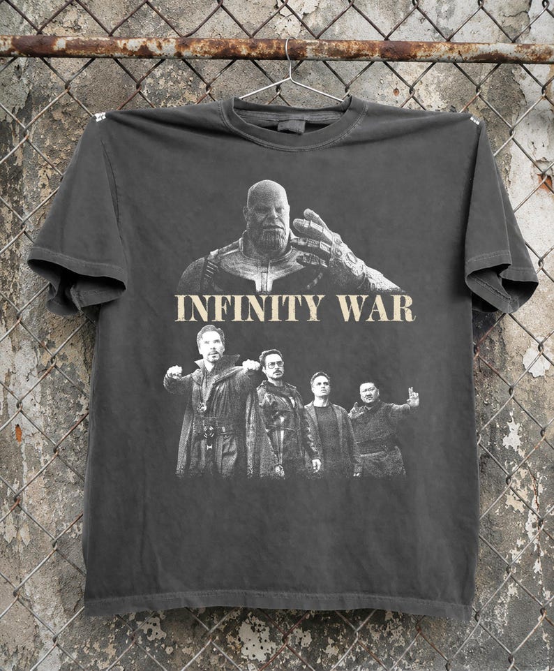 K&ouml;nnte beinhalten: Dunkelgraues T-Shirt mit einer Grafik aus dem Film "Infinity War". Das Design zeigt Thanos und andere Charaktere. Die Worte "INFINITY WAR" sind in Beige &uuml;ber die Mitte des T-Shirts gedruckt.