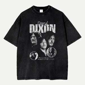 Puede incluir: Camiseta negra con un gráfico desgastado de Daryl Dixon y el texto "Daryl Dixon". El diseño incluye múltiples imágenes del personaje y la cita: "Luchamos por nuestro futuro. No luchamos por la venganza."