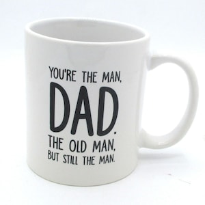 May include: A set of three ceramic mugs with a speckled, matte finish. The mugs are in shades of cream, light gray, and dark gray. Each mug has a simple, minimalist design and a rounded handle.