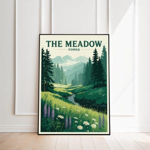 May include: A framed art print titled "The Meadow Forks" depicts a serene landscape. The artwork showcases a vibrant green meadow, a winding stream, and towering evergreen trees. Purple and white wildflowers dot the foreground, with mountains in the distance.