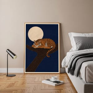 May include: A framed wall art print featuring a tiger with orange and black stripes resting on a dark brown tree branch against a deep blue background with a large, pale yellow circular moon positioned behind the tiger's head.