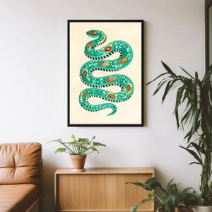 Peut inclure: Une impression d'art murale encadrée représentant un serpent turquoise stylisé avec un motif géométrique répétitif en orange, blanc et noir. Le serpent est représenté dans une pose sinueuse en forme de S sur un fond crème clair uni.
