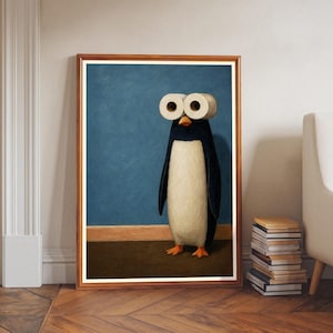 Pode incluir: Uma impressão de arte emoldurada apresentando um pinguim com dois rolos de papel higiênico brancos como olhos. O pinguim tem costas pretas, barriga branca e pés laranja, posicionado contra uma parede azul e um chão marrom escuro.