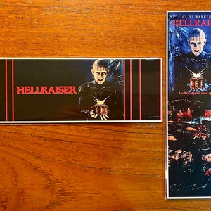 May include: Two promotional items featuring the movie "Hellraiser." One is a rectangular sticker with the title and a character image. The other is a tall bookmark with movie art and the tagline "Hell tear your soul apart."