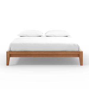May include: A wooden bed frame with a light brown finish. The bed is made up with white sheets and two white pillows. The bed frame has a simple, modern design.
