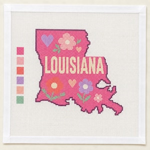 May include: A square needlepoint canvas featuring a hot pink map of Louisiana with the word LOUISIANA printed in yellow. The map is decorated with light pink, orange, and purple flowers and hearts. A color palette guide is on the left side.
