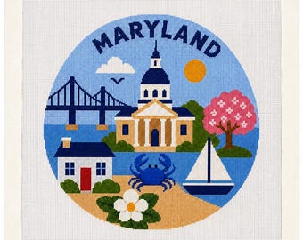 Könnte beinhalten: Eine Stickvorlage mit einem kreisförmigen Design und dem Wort MARYLAND am oberen Rand. Die Szene zeigt eine blaue Brücke, ein Gebäude mit Kuppel, ein weißes Haus mit roter Tür, eine blaue Krabbe, ein Segelboot, einen rosa Baum und eine weiße Blume.