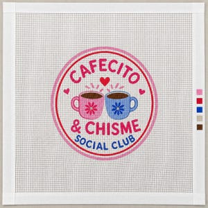 May include: A square needlepoint canvas featuring a circular logo with the text CAFECITO & CHISME SOCIAL CLUB. The design includes a pink mug and a blue mug with flower accents, surrounded by small red hearts, all enclosed in a pink border.