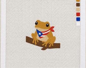 Könnte beinhalten: Ein quadratisches Stickbild auf Stramin, das einen hellbraunen Frosch auf einem dunkelbraunen Ast zeigt. Der Frosch trägt ein Halstuch mit dem Muster der Flagge von Puerto Rico, bestehend aus roten und weißen Streifen, einem blauen Dreieck und einem weißen Stern.