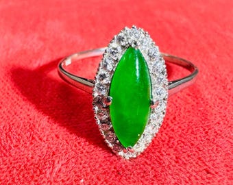 May include: A marquise-shaped green jade ring set in silver with a halo of small diamonds.