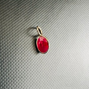 以下が含まれることがあります： 赤い楕円形の宝石が付いた金のペンダント