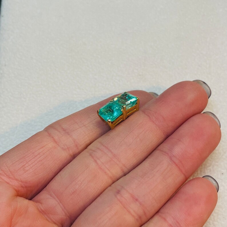 May include: A gold ring with a large, rectangular, emerald-cut, light blue gemstone.