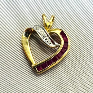 May include: A heart-shaped pendant crafted from yellow metal, featuring a channel of square-cut deep red rubies along one side and a curved silver-toned accent set with small clear stones across the top, complete with a top bail for hanging.