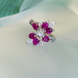 以下が含まれることがあります： 花柄のデザインにルビーとダイヤモンドの石がセットされたシルバーリングです。