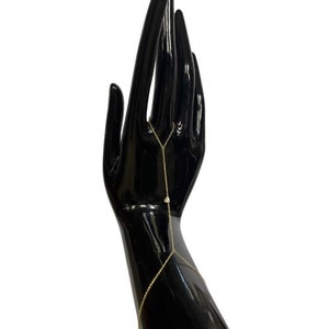 May include: A gold chain bracelet with small triangle-shaped charms. The bracelet is worn on a black mannequin hand.