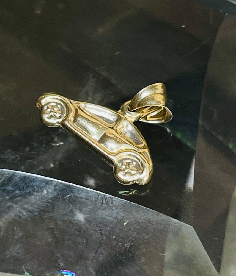 May include: A gold-colored car charm pendant. The charm is detailed and has a realistic car shape.