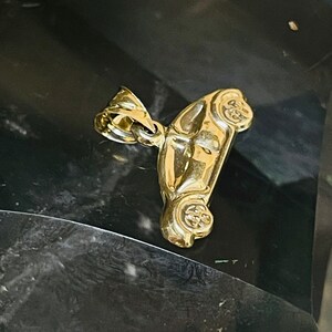 May include: A gold-colored car charm pendant. The charm is detailed and has a realistic design.