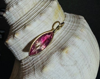 Könnte beinhalten: Ein rosa-goldener Anhänger mit einem tropfenförmigen Edelstein und einer goldenen Öse.