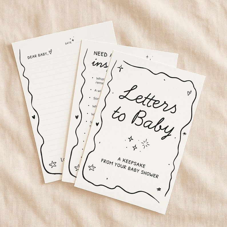 May include: A set of cream-colored baby shower keepsake cards. The cards have black handwritten text that reads "Letters to Baby" and "Dear Baby". The cards are decorated with stars, hearts, and a wavy border.