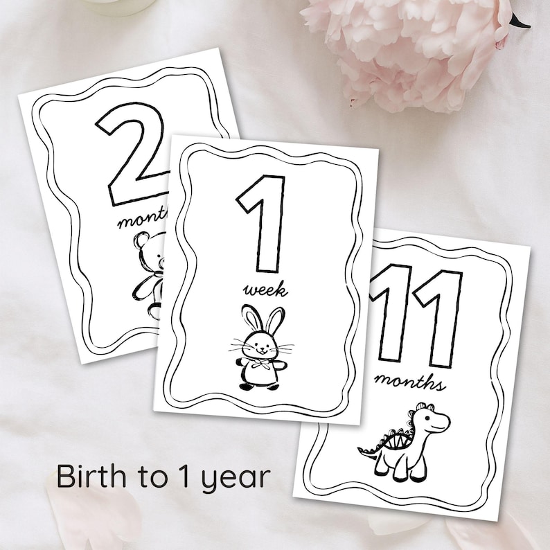 Peut inclure: Trois cartes &eacute;tapes pour b&eacute;b&eacute; en noir et blanc avec des bords festonn&eacute;s. Les cartes affichent les chiffres 2, 1 et 11, avec les mots "mois" et "semaine" &eacute;crits en dessous. Chaque carte pr&eacute;sente un animal de dessin anim&eacute; diff&eacute;rent : un ours, un lapin et un dinosaure. Le texte "De la naissance &agrave; 1 an" est en bas.