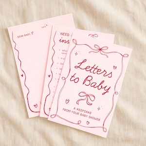 May include: Pink "Letters to Baby" keepsake set with red decorative accents. The set includes a cover with the title, a lined letter page with "Dear Baby" and a date field, and an instruction page.