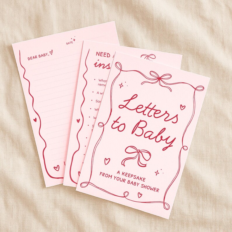 May include: Pink "Letters to Baby" keepsake set with red decorative accents. The set includes a cover with the title, a lined letter page with "Dear Baby" and a date field, and an instruction page.