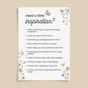 Op de afbeelding: Een witte kaart met de woorden "need a little inspiration?" in zwart schrift. De kaart bevat een lijst met prompts, met bloemen- en vlinderillustraties. De prompts zijn ontworpen om reflectie en gedachten te inspireren.