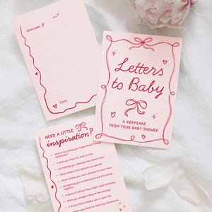 May include: Pink stationery set with the text "Letters to Baby" and "A Keepsake From Your Baby Shower." Includes a notepad with "Dear Baby" and a list of prompts. Decorative bows and hearts adorn the pages.