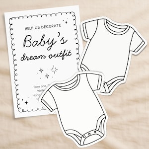 Op de afbeelding: Een witte kaart met de tekst "Help us decorate Baby's dream outfit" en twee witte babyromper uitsparingen. De kaart heeft een decoratieve rand en steraccenten. De rompers zijn blanco, klaar om te worden ontworpen.
