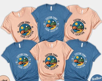 May include: A collection of six t-shirts in peach and blue hues. Each shirt features a circular graphic with a tent, mountains, sun, and the text "CUSTOM CAMP YOUR LOCATION 20 25".